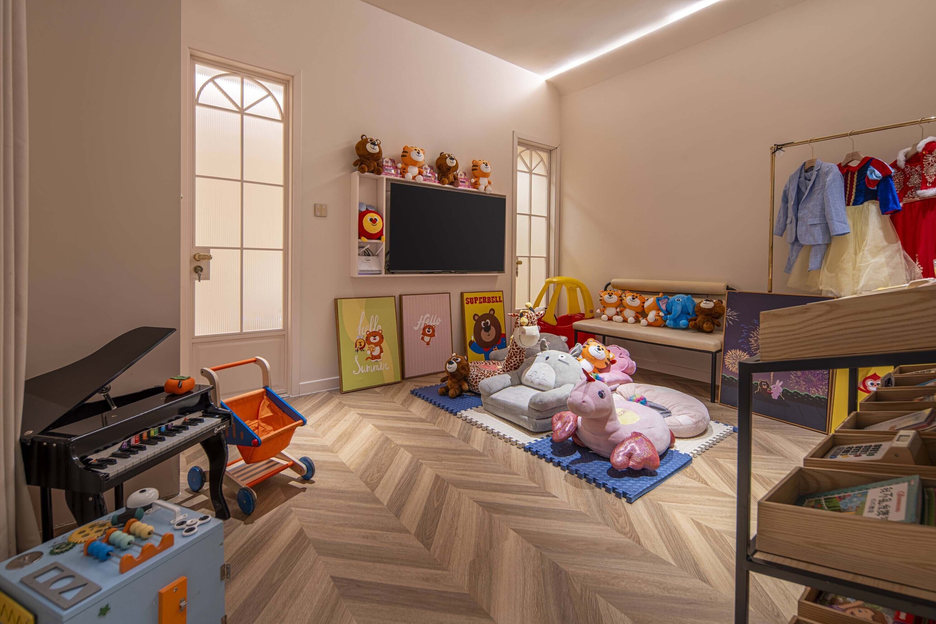 A child's playroom with a piano, toys, and a television.