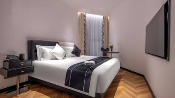 Habitación de hotel moderna con una cama grande, una mesita de noche con un teléfono, una pequeña mesa con un florero y un espejo grande en la pared.