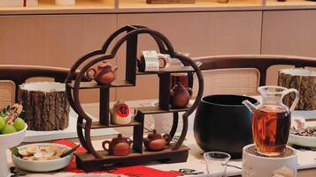Ein Esstisch, gedeckt mit traditionellen Utensilien für eine chinesische Teezeremonie, darunter Teekannen, Tassen und eine Teekanne auf einem Sockel.