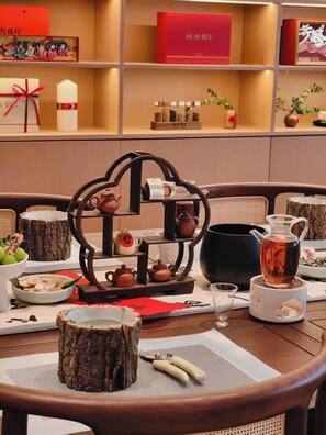 Uma mesa de jantar posta com objetos tradicionais de cerimônia do chá chinesa, incluindo bules, xícaras e um bule sobre um suporte.