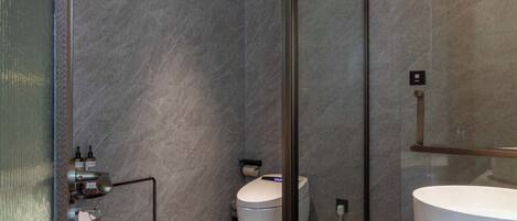 A modern bathroom with a glass-enclosed shower, a standalone toilet, and a vanity with a large mirror.