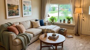 Ein Wohnzimmer mit einer Couch, einem Couchtisch und einem Fenster mit Vorhängen.