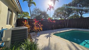 Ein Garten mit Schwimmbecken, Holzzaun und verschiedenen Pflanzen.