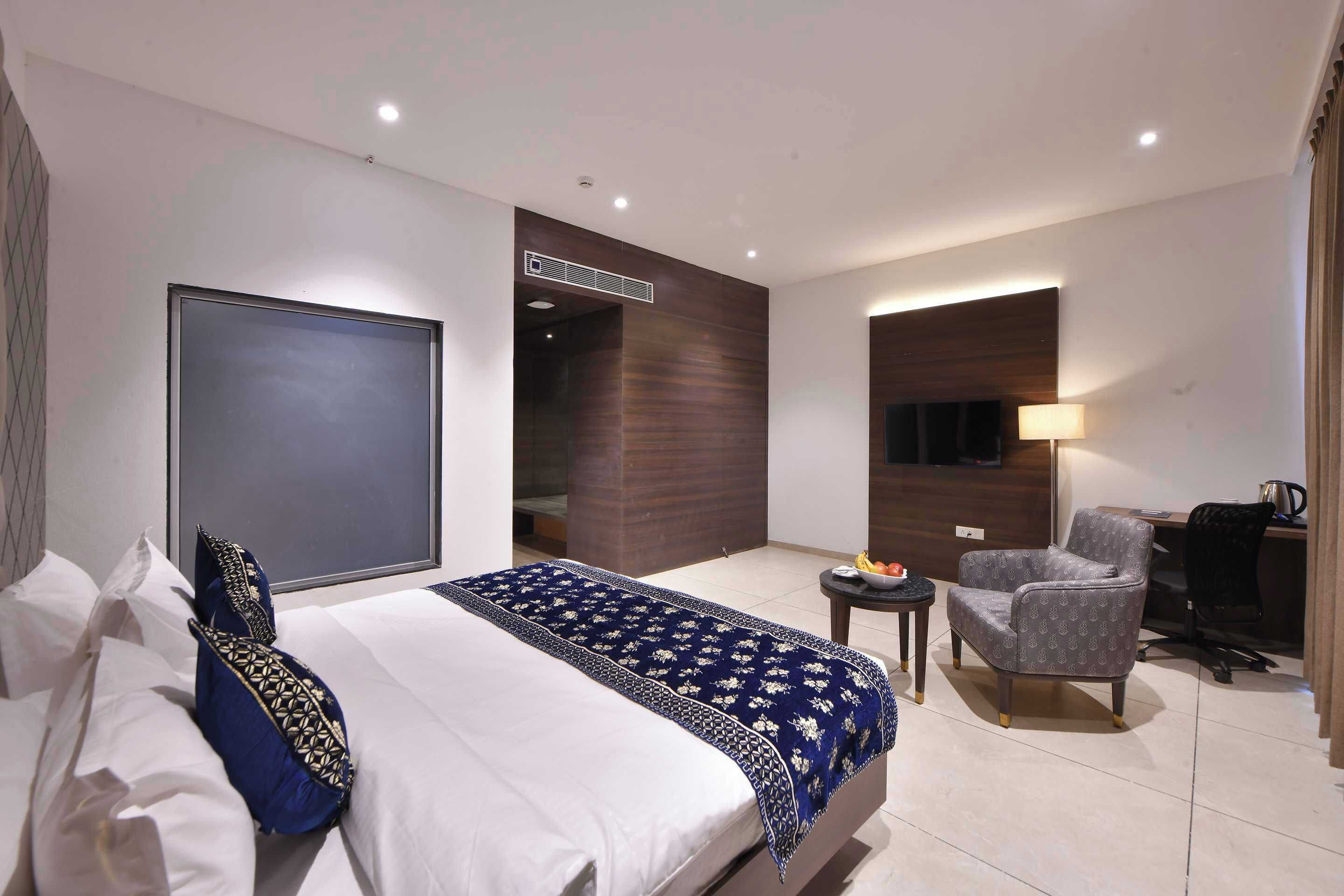 Een hotelkamer met een bed, een stoel, een bureau en een kleine tafel.