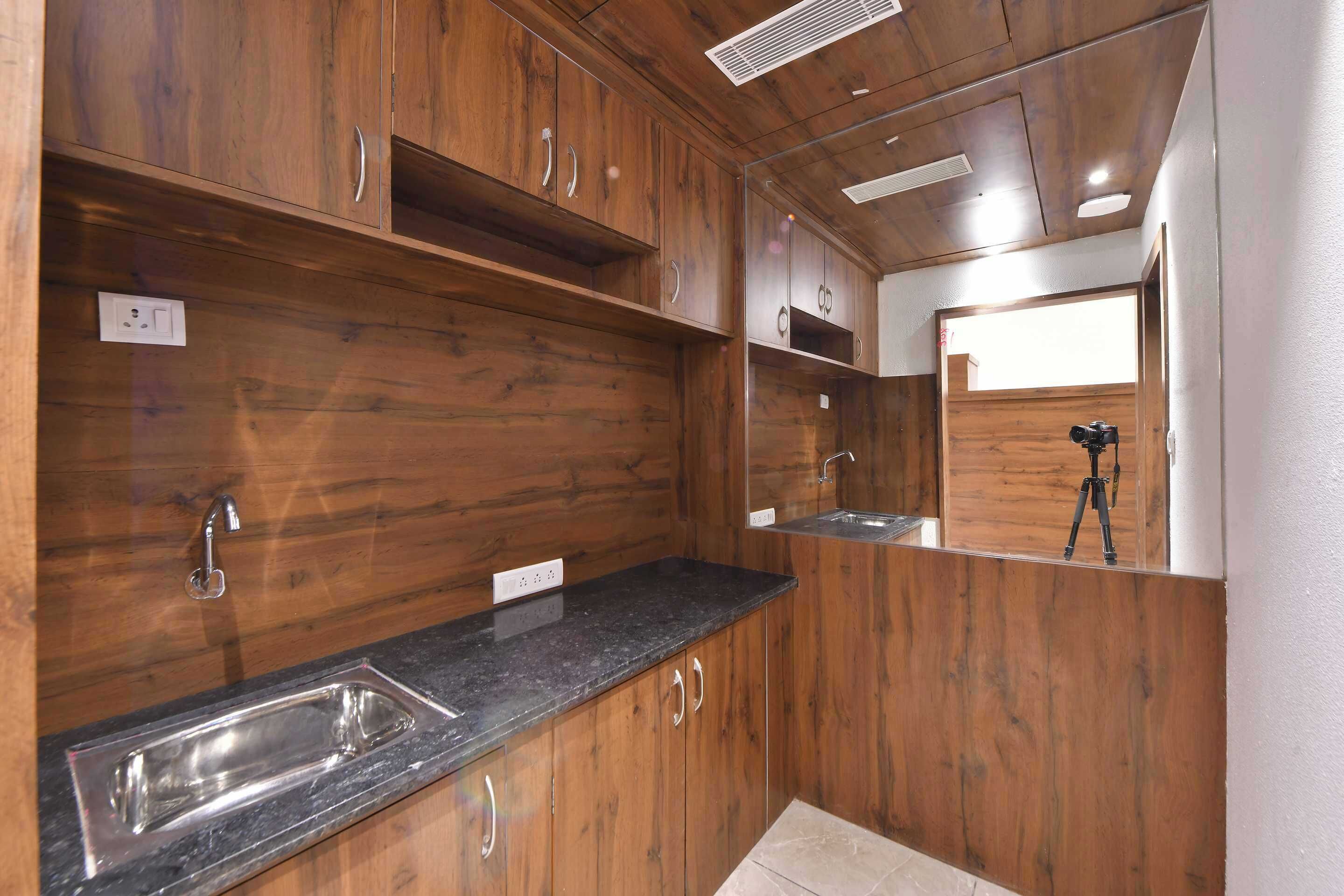 A modern kitchen with wooden cabinetry, a granite countertop, and a stainless steel sink.