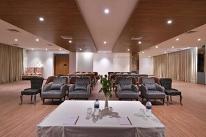 A conference room with rows of chairs, a table with a white tablecloth, and a vase with flowers. - Clubhouse Hotel Morbi (Morbi)