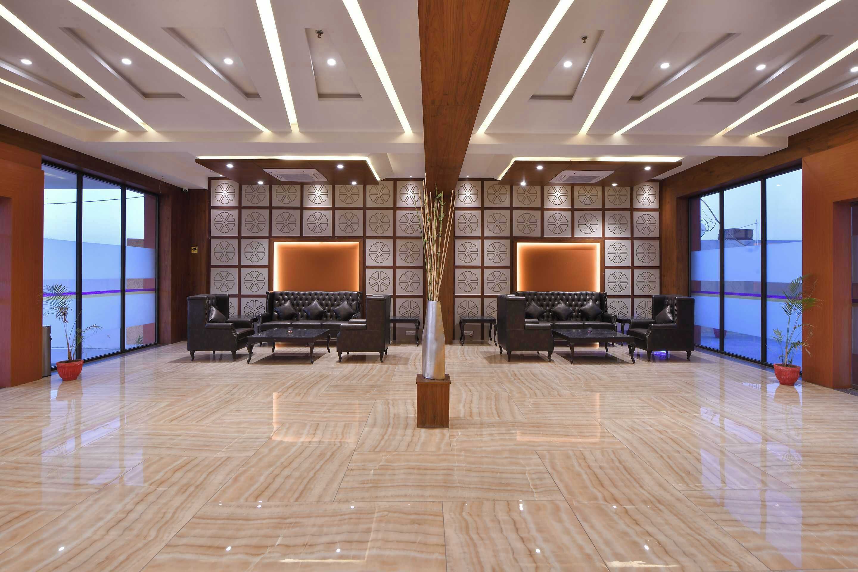 Un lobby amplio con piso de mármol pulido, dos sofás con cojines, un jarrón decorativo y un revestimiento de pared estampado.