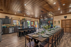 A spacious kitchen with wooden cabinets, a large island, and bar stools. - Luxury BRAND NEW 8bdrm Cabin-Pool-Arcades-Gazebo (Sevierville)