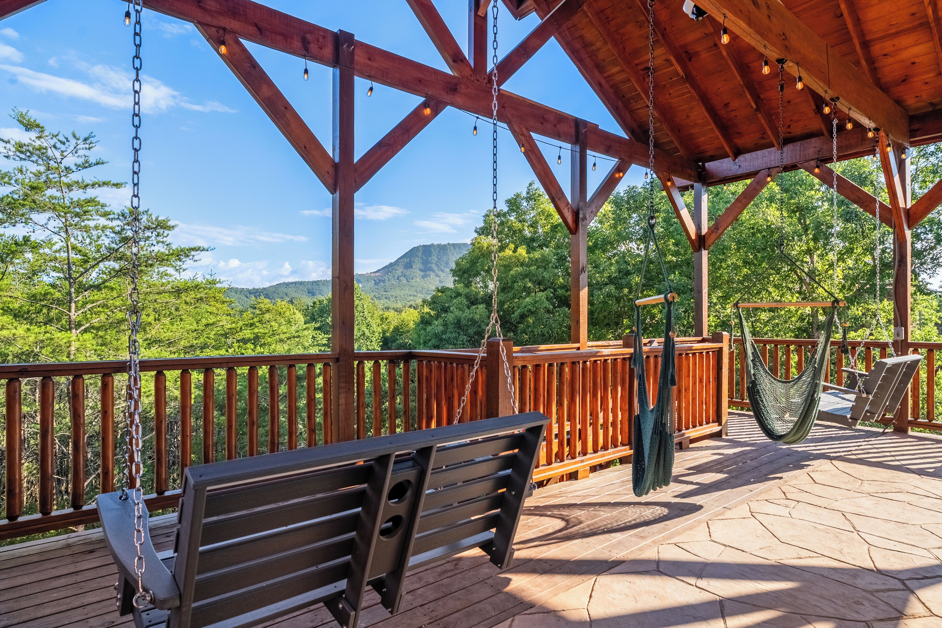 Une terrasse en bois avec une balançoire, un hamac et un banc.