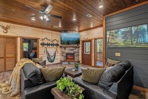 Un intérieur de chalet chaleureux avec une cheminée en pierre, des canapés en cuir et un hamac.