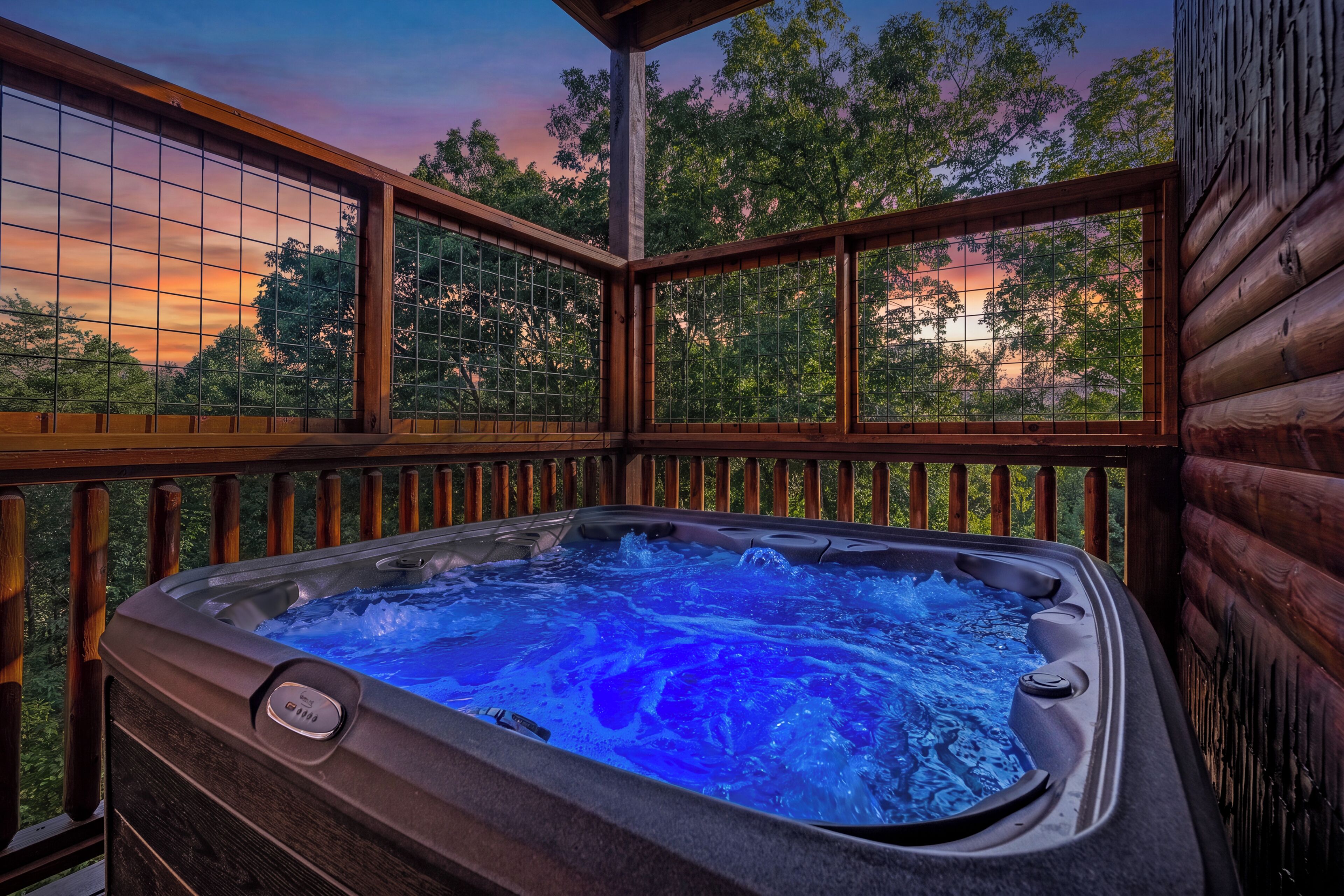 A hot tub on an outdoor deck with a view of trees and a sunset.