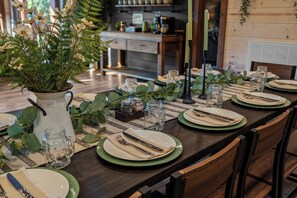 A dining table set with plates, cutlery, and glassware, surrounded by chairs. - Luxury BRAND NEW 8bdrm Cabin-Pool-Arcades-Gazebo (Sevierville)