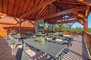 Eine Terrasse im Freien mit Holztischen und -bänken, einem Kamin aus Stein und Blick auf die umliegende Landschaft.