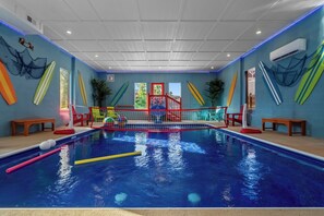 Ein Hallenbad mit Sprungbrett, Schwimmnudeln und einem roten Sicherheitsnetz.