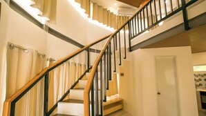 A staircase with wooden steps and black railings, leading to a landing with a white door and a tiled backsplash. - Fizz Diving Resort (Panglao)