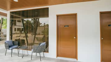 Una habitación moderna con un ventanal grande, dos puertas y una zona de estar con sillas y una mesa.