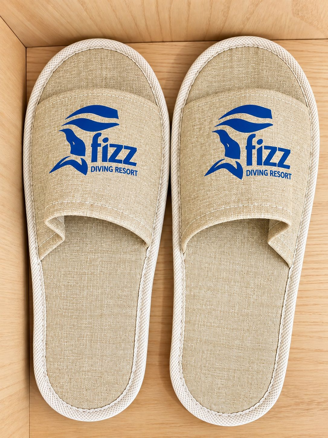 A pair of beige slippers with a logo and text indicating they are from Fizz Diving Resort.