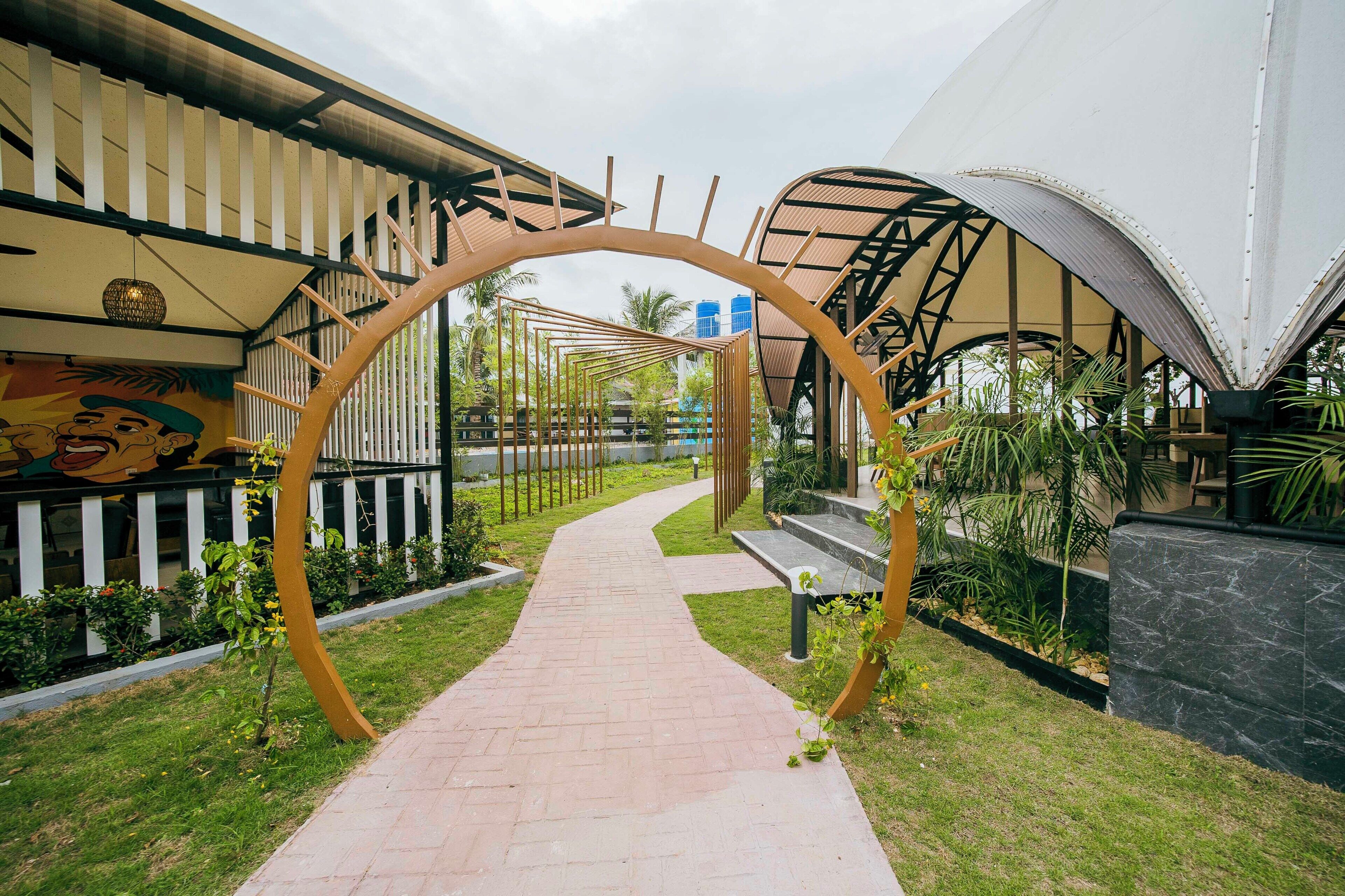 A pathway leading through a garden area with a distinctive arch structure.