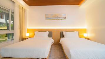 A hotel room with two beds, a painting on the wall, and a window with curtains.