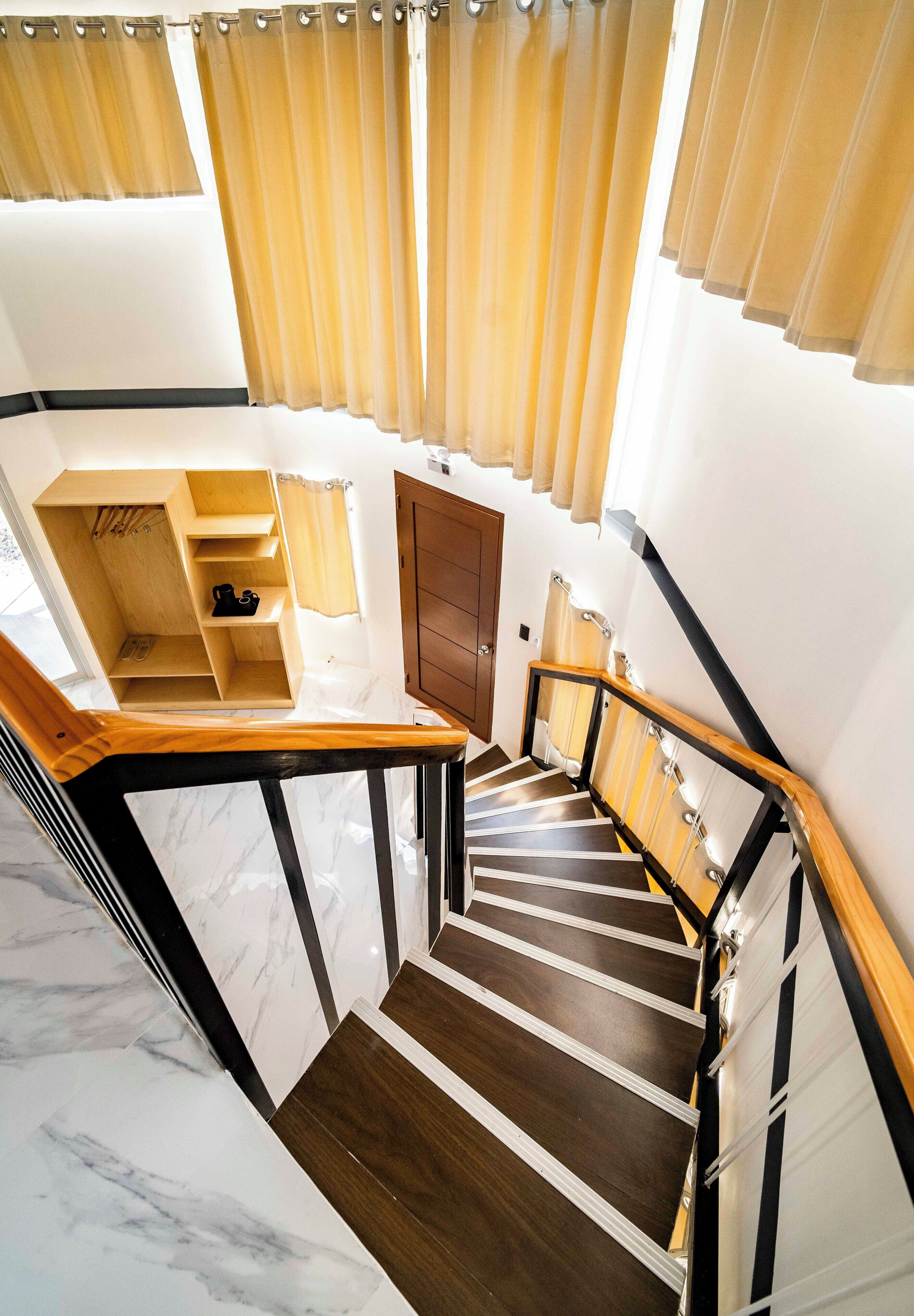 Ein mehrstöckiger Innenraum mit einer Holztreppe, einem Holzkasten mit Regalen und einer Tür.