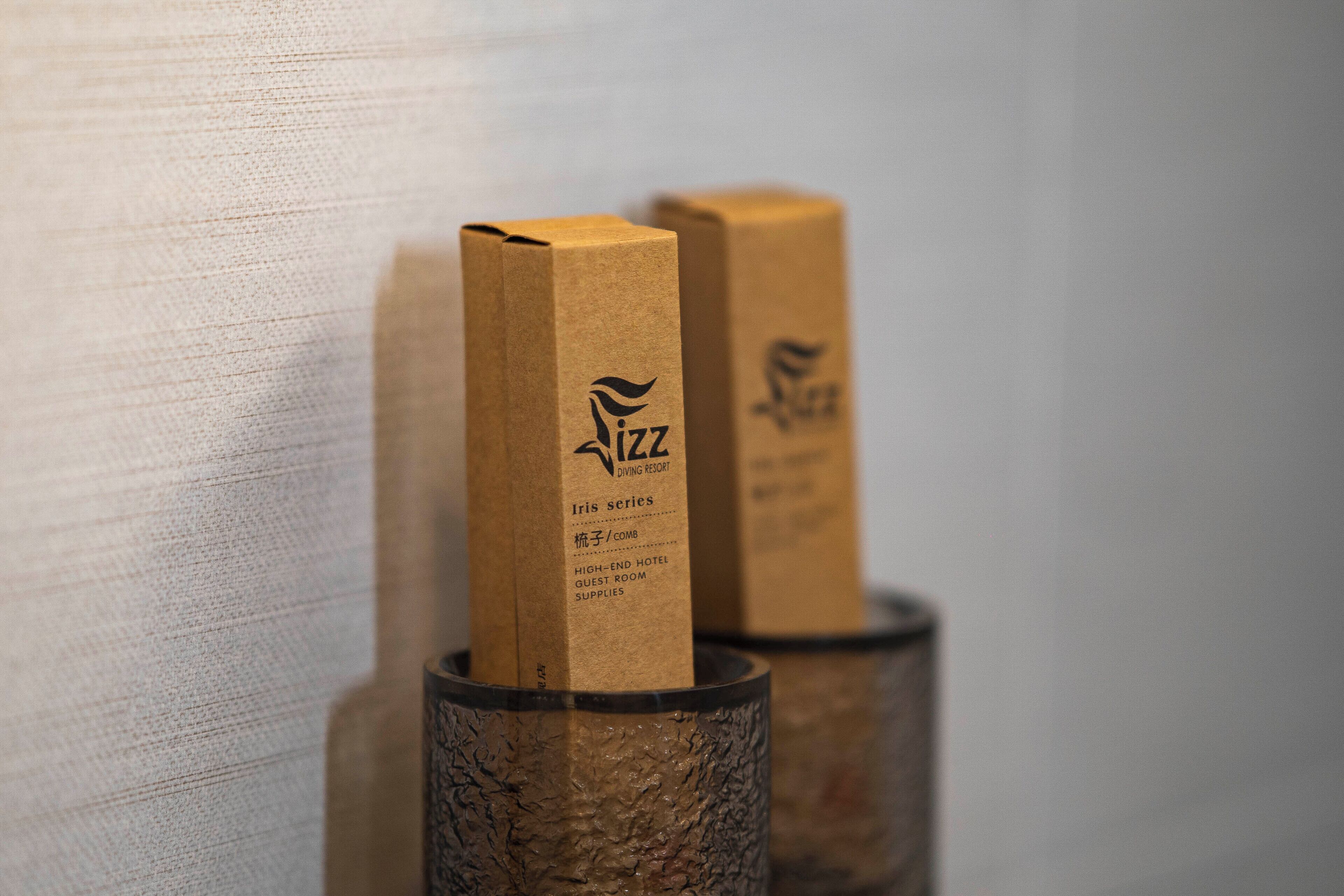 Two brown paper bags with the logo 'iZZ Diving Resort' and text indicating 'Iris series,' 'High-End Hotel,' 'Guest Room,' and 'Supplies.'