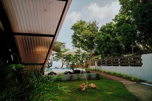 A modern outdoor area with a pool, lounge chairs, and a wooden pergola.