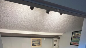 A room with a brown carpet, a white bench, a piano, and a framed picture on the wall. - Lovely 2-bedroom house with AC in Sarasota close to beaches (Sarasota)