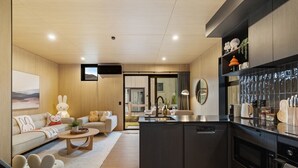 A modern kitchen with a central island, a dining area with a sofa and table, and a living area with a sofa and decorative pillows.