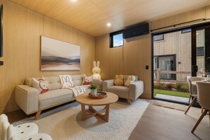 A modern living room with a sofa, two armchairs, a coffee table, and a large window.