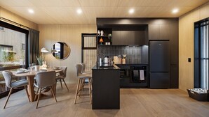 A modern kitchen with a central island, dark cabinetry, and a dining area with a round table and chairs.