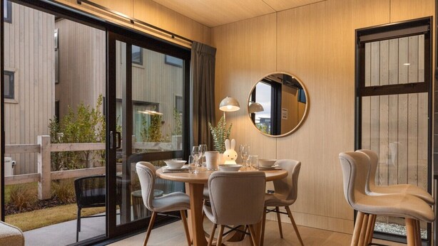 A dining area with a round table, chairs, and a mirror on the wall.