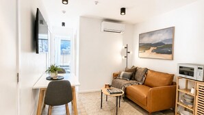 En moderne stue med en sofa, et spisebord, et fjernsyn og et billede på væggen.