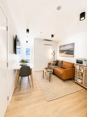 Ein modernes Wohnzimmer mit Sofa, Esstisch, Fernseher und einem Bild an der Wand.