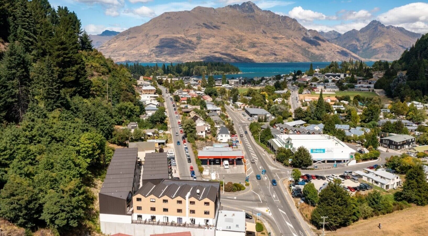 Uma cidade com uma estrada principal, edifícios e uma montanha ao fundo.