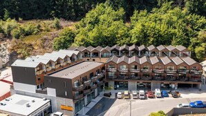 Et hotel i flere etager med moderne arkitektur, med altaner og en parkeringsplads med flere biler.