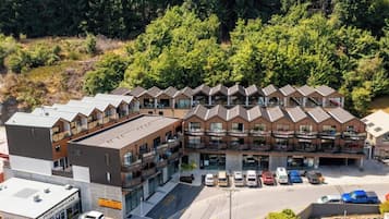 A multi-story hotel with a modern architectural design, featuring balconies and a parking area with several cars.