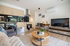 Une cuisine moderne équipée d’appareils électroménagers, un coin repas avec des chaises, un téléviseur et un coin salon confortable avec un canapé et une table basse.