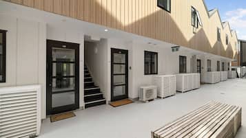 A row of hotel rooms with individual entrances, a staircase, and a row of air conditioning units.