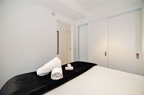 Ein Hotelzimmer mit einem Bett, einem schwarzen Kopfteil, weißen Wänden und einer Tür.