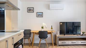 A modern kitchen with a dining area, a flat-screen TV, and two framed pictures on the wall.