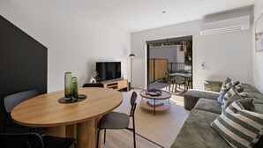 A modern living room with a dining area, a sofa, a TV, and a small table with a lamp. - Prime Location with mountain views (Queenstown)