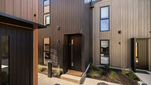 A modern building with a dark exterior, multiple windows, and a visible door. - Prime Location with mountain views (Queenstown)