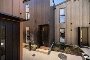 A modern building with a dark exterior, multiple windows, and a visible door. - Prime Location with mountain views (Queenstown)