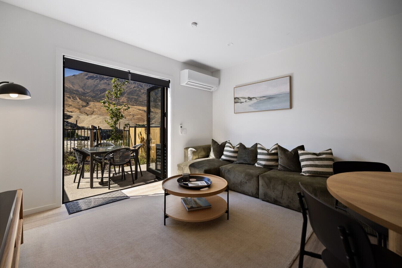 A modern living room with a sofa, a round coffee table, and a dining area with a table and chairs.