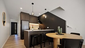 A modern kitchen with a central island, black bar stools, and a round wooden table with chairs. - Prime Location with mountain views (Queenstown)