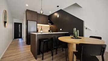 A modern kitchen with a central island, black bar stools, and a round wooden table with chairs.