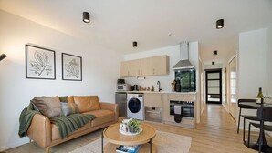 En modern lägenhet med vardagsrum, kök och matplats.
