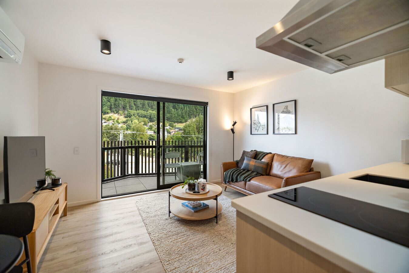 Un appartement moderne doté d’un balcon, d’un canapé, d’une table basse et d’un téléviseur.