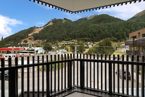 Ein Balkon mit Blick auf eine gebirgige Landschaft, eine Tankstelle und ein modernes Gebäude.