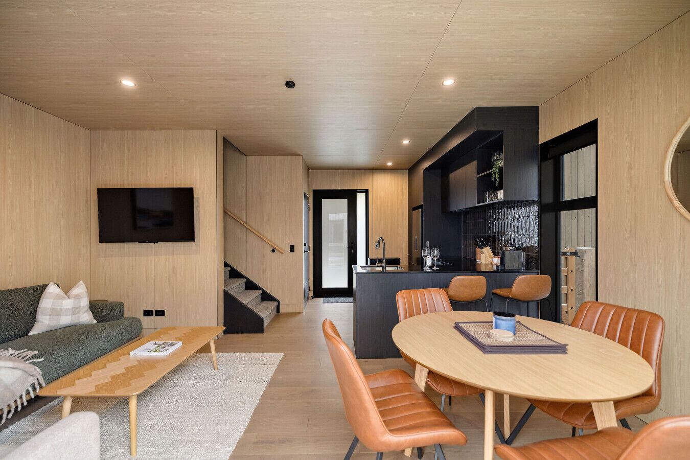 A modern living room with a sofa, coffee table, and dining area with chairs.